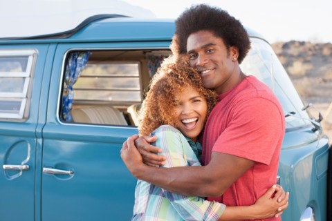 Couple in front of mini van during road trip