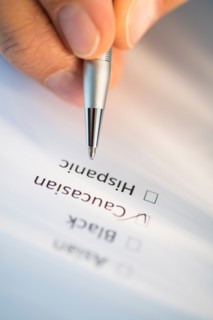 Close-up of hand filling out form.