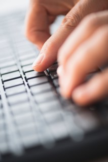 Close-up of hands typing on keyboard.