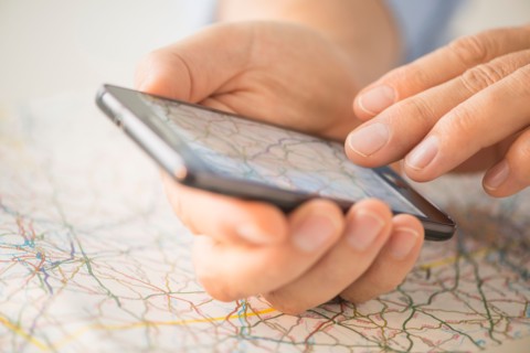 Close-up of hand using smartphone over map.