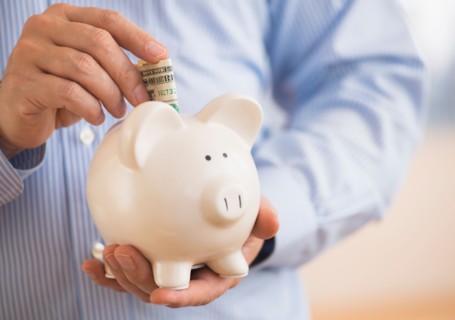 Man inserting money into piggy bank.