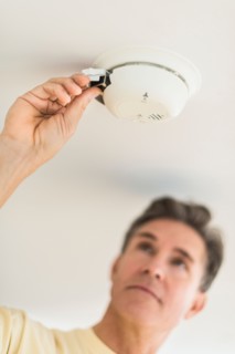 Man changing battery in smoke alarm.
