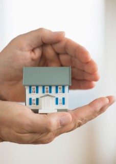 Hands holding model house.