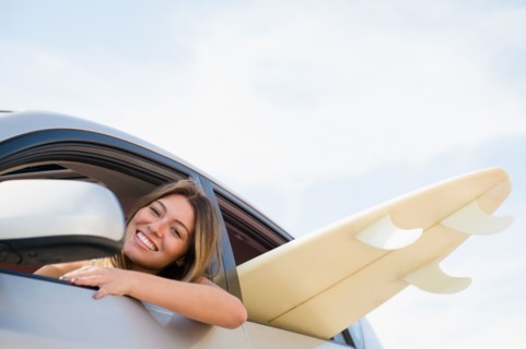 Woman driving car with surfboard inside. Photo: Jamie Grill