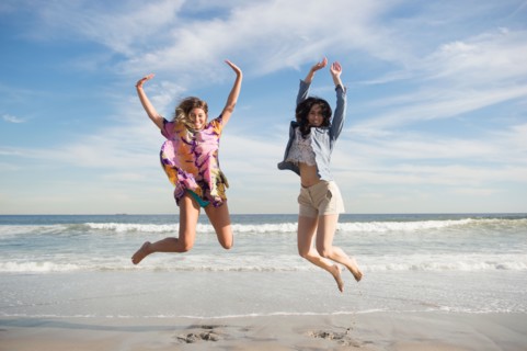 Two young women jumping on beach. Photo : Jamie Grill