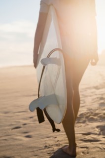 Female surfer walking on beach at sunset. Photo : Jamie Grill