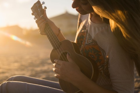 Woman playing ukulele at sunset. Photo : Jamie Grill