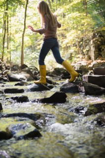 Woman walking on rocks in stream. Photo: Jamie Grill
