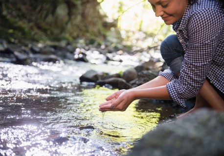 Woman crouching by stream. Photo : Jamie Grill