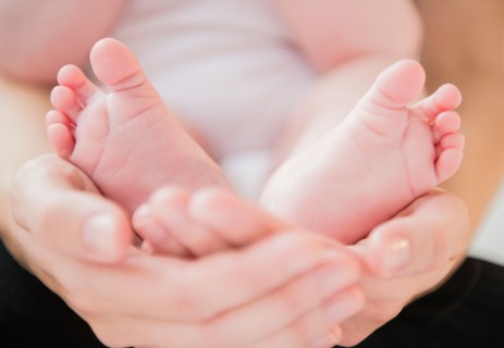 Mother holding feet of baby boy (2-5 months). Photo: Jamie Grill