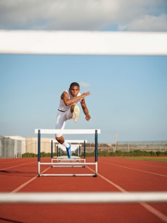 Boy (12-13) hurdling on running track. Photo: Erik Isakson