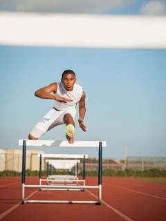 Boy (12-13) hurdling on running track. Photo: Erik Isakson