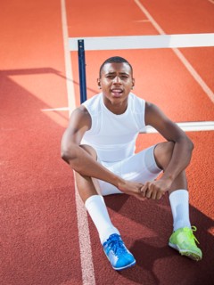 Portrait of boy (12-13) resting on running track. Photo: Erik Isakson