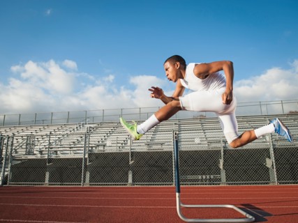 Boy (12-13) hurdling on running track. Photo: Erik Isakson