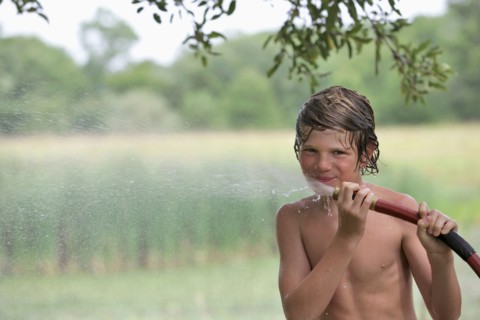 Boy (10-11) drinking from water hose in summer. Photo : pauline st.denis