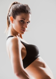 Portrait of young woman exercising, studio shot. Photo : Mike Kemp