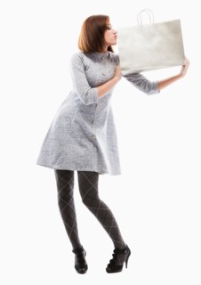 Young woman holding shopping bag, studio shot. Photo : Mike Kemp