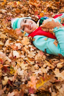 Portrait of smiling young woman lying on autumn leaves . Photo : Mike Kemp