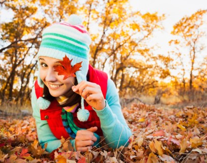 Portrait of smiling young woman lying on autumn leaves . Photo : Mike Kemp