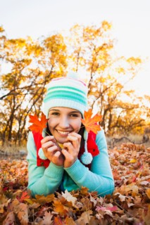 Portrait of smiling young woman lying on autumn leaves . Photo : Mike Kemp