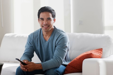 Portrait of smiling mid adult man sitting on sofa. Photo : Dan Bannister