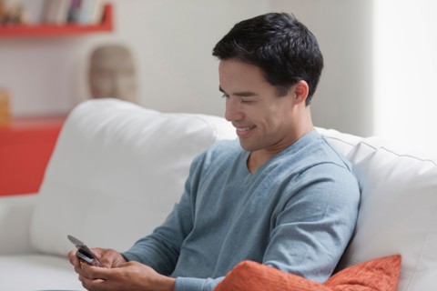 Man texting in living room. Photo : Dan Bannister