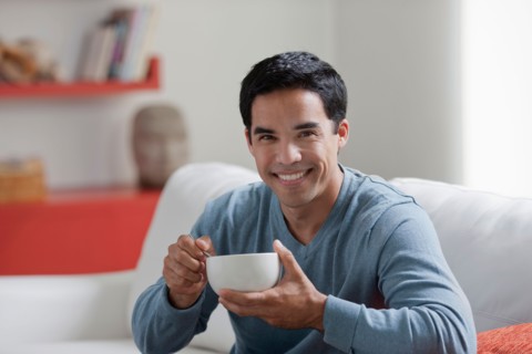 Portrait of man with bowl in living room. Photo : Dan Bannister