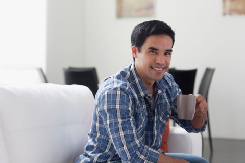 Portrait of man drinking coffee in living room. Photo : Dan Bannister