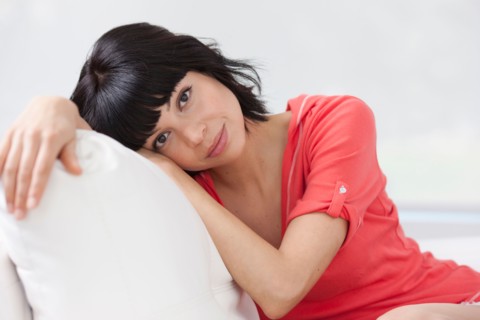 Young woman sitting on sofa. Photo : Dan Bannister