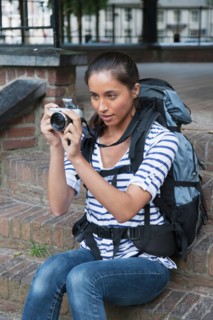 Portrait of young woman with backpack and camera. Photo : Jan Scherders