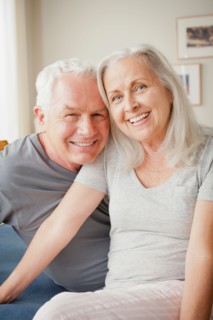 Senior couple sitting on bed in close embrace. Photo : Rob Lewine