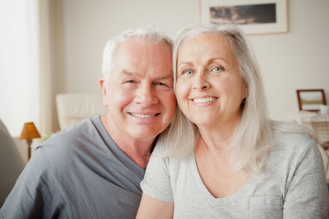 Senior couple sitting on bed in close embrace. Photo : Rob Lewine