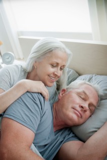 Portrait of senior couple laying in bed in morning. Photo : Rob Lewine