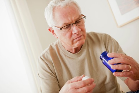 Senior man holding medicine flask. Photo : Rob Lewine