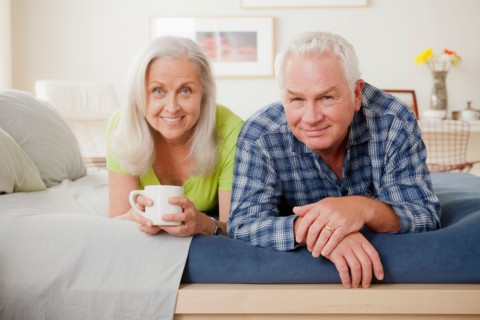 Portrait of senior couple laying on bed. Photo : Rob Lewine