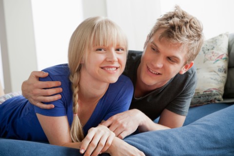 Portrait of couple lying on bed and smiling. Photo : Rob Lewine