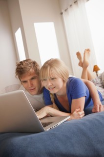 Couple lying on bed using laptop. Photo: Rob Lewine