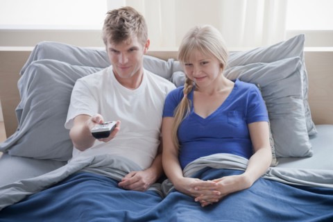 Couple watching television in bed. Photo : Rob Lewine