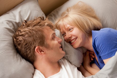 Elevated view of laughing couple lying in bed. Photo : Rob Lewine