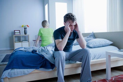 Angry couple sitting on bed. Photo : Rob Lewine