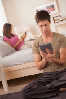 Couple using mobile phone and digital tablet. Photo : Rob Lewine