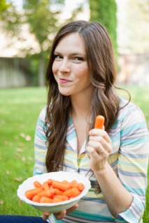 Portrait of mid adult woman eating carrots. Photo : Jessica Peterson
