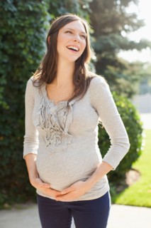 Pregnant mid adult woman standing in front of entrance door. Photo : Jessica Peterson