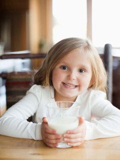 Girl (4-5) drinking milk in kitchen. Photo : Jessica Peterson