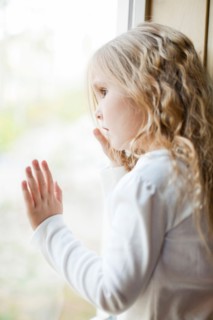 Girl (4-5) looking through window. Photo : Jessica Peterson