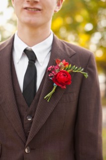 Mid section of groom wearing full suit decorated with boutonniere. Photo: Jessica Peterson