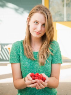 Portrait of young woman holding raspberries. Photo : Jessica Peterson