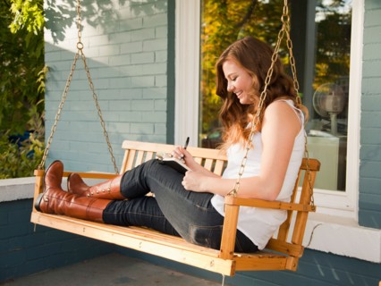 Young woman sitting on swing and making notes. Photo : Jessica Peterson