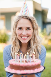 Portrait of young woman holding birthday cake. Photo : Jessica Peterson