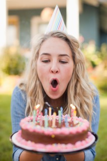 Portrait of young woman blowing birthday candles. Photo : Jessica Peterson